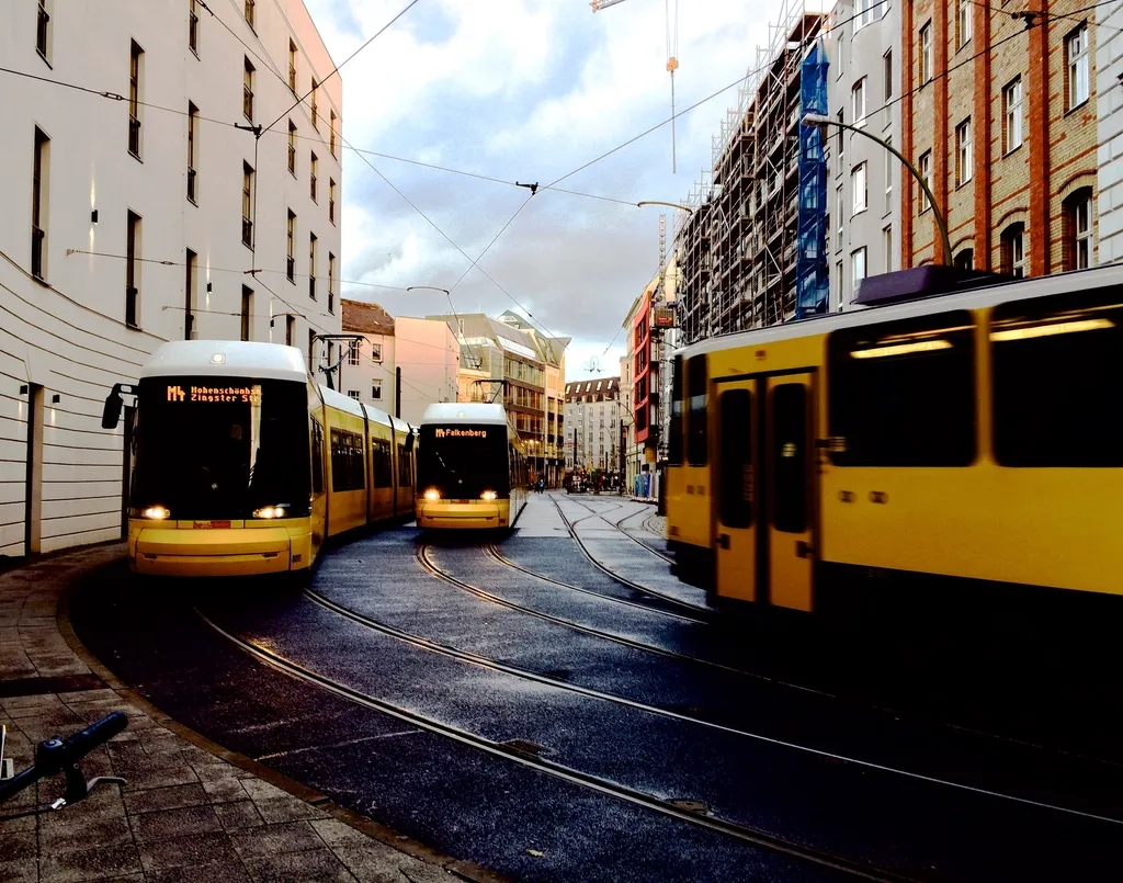 Yellow trams passing each other on a city street lined with apartment buildings