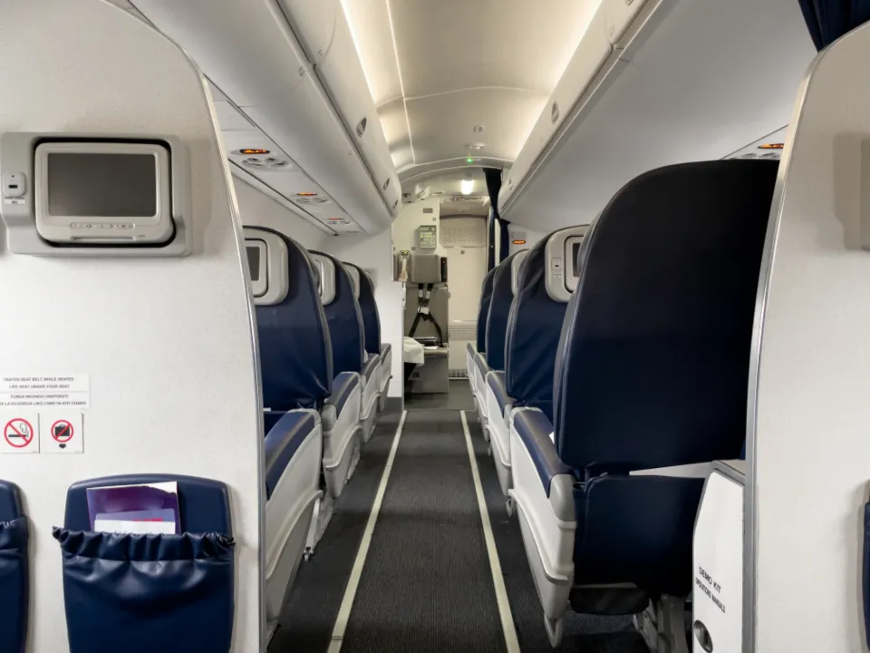 Rows of empty blue economy seats seen down the aisle of an aircraft cabin