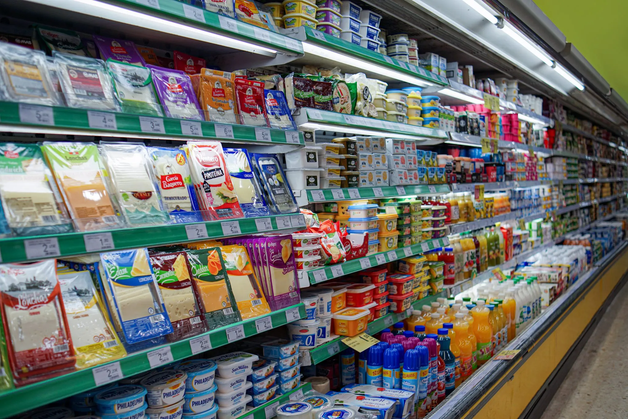A chilled supermarket aisle stacked with packaged food and price labels