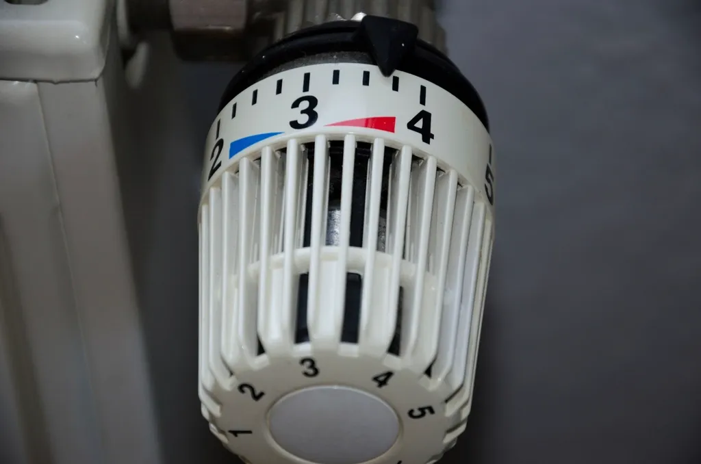 Close-up of a white thermostatic radiator valve numbered one to five, fitted to a household radiator